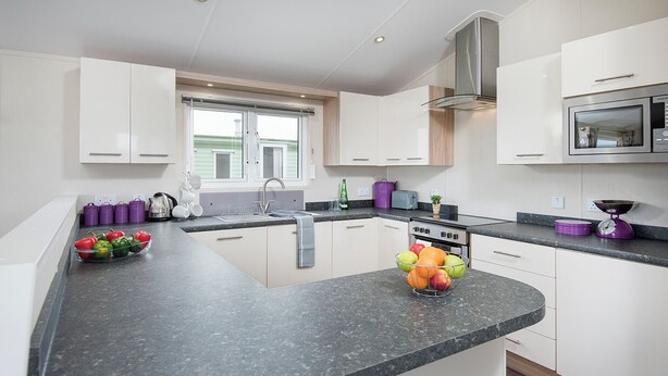 A modern kitchen with a granite countertop, stainless steel appliances, and a window providing natural light.