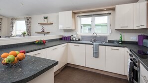 A modern kitchen with white cabinets, a granite countertop, a built-in oven, and a window with a view.