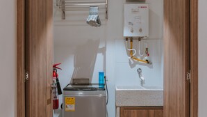 Un baño con un calentador Bosch, un lavamanos y un extintor.