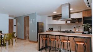 A modern kitchen with a central island, bar stools, and a dining area with chairs.