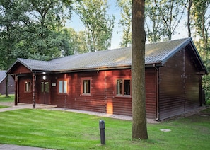 A wooden cabin with a sloped roof, a porch, and a well-maintained lawn.