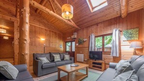 Ein Holzblockhaus-Interieur mit einer Couch, einem Couchtisch, einem Fernseher und Holzwänden.