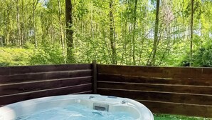 Ein Whirlpool, umgeben von einem Holzzaun, mit Blick auf einen Wald.