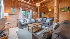 Ein rustikales Holzblockhaus-Interieur mit einer Sofagarnitur, einem Holztisch und einer Hängelampe.