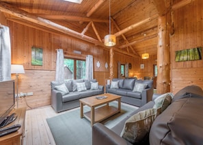 A log cabin interior with a sofa set, a wooden coffee table, and a hanging light fixture. - 4 bedroom accommodation in Ellesmere (Ellesmere)