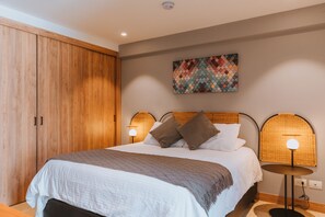 A bedroom with a large bed, a wardrobe, a wall-mounted artwork, and two bedside lamps. - Spacious 710ft Loft -Front Desk 24/7✔- Alori 202 (Medellín)