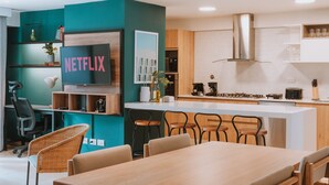 Eine moderne Küche mit Kochinsel, Holzschränken und einem integrierten Fernseher, der "NETFLIX" anzeigt.