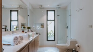 Ein modernes Badezimmer mit großem Spiegel, zwei Waschbecken, Toilette und Duschbereich.