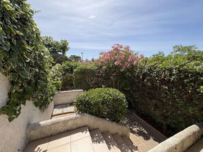 Un escalier entouré de verdure, avec un ciel dégagé au-dessus.