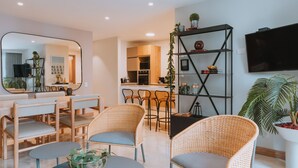 A modern living room with wicker furniture, a dining area, and a kitchen in the background. - 2 bedroom apartment in medellãn (Medellín)
