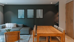 A modern living room with a grey sofa, a wooden dining table, and three framed artworks on the wall. - 2 bedroom apartment in medellãn (Medellín)