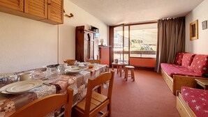 Ein gemütliches Zimmer mit Essbereich, einer Couch und einem fenster mit Vorhängen.