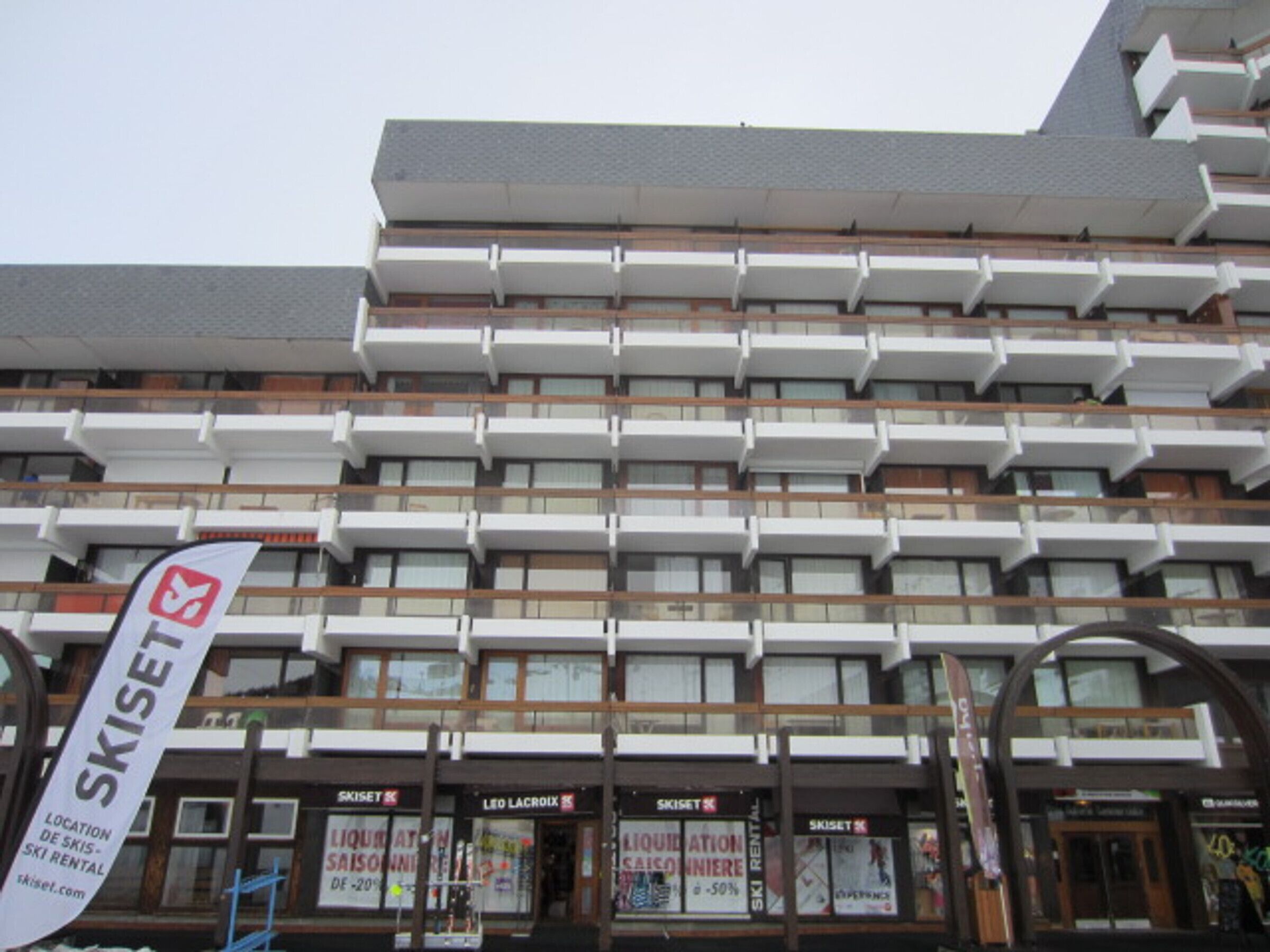 A multi-story building with a modern architectural design, featuring balconies and large windows.