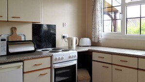 A compact kitchen with a stove, oven, and microwave. There is a window with curtains, a sink, and cabinets. - 2 bedroom accommodation in Wroxham, Norfolk Broads (Wroxham, Norfolk Broads)