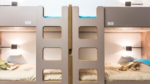 Une chambre avec deux lits superposés, chacun doté d’une petite fenêtre et d’une lampe de chevet.
