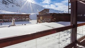 Un paysage de montagne enneigé, avec un bâtiment à plusieurs étages et un télésiège en arrière-plan.