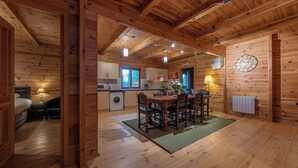 L’intérieur d’une cabane en bois comprend un coin repas, une cuisine et un lit visible.