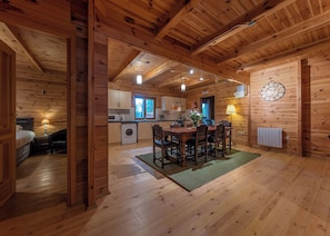 L’intérieur d’une cabane en bois comprend un coin repas, une cuisine et un lit visible.