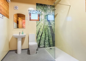 A bathroom with a toilet, sink, shower, and a large window with a tropical wallpaper. - Woodland Hawthorn Lodge (Ellesmere)