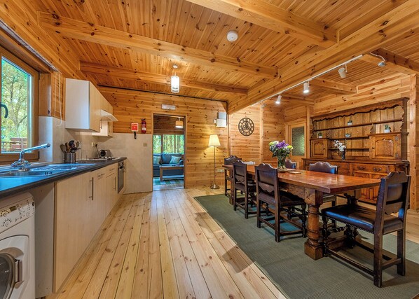 A wooden cabin interior with a kitchen, dining area, and a cozy seating area. - Woodland Hawthorn Lodge (Ellesmere)