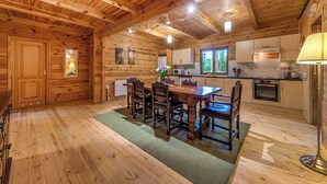 L’intérieur d’un chalet en bois comprend une table à manger, des chaises, un coin cuisine et une fenêtre.