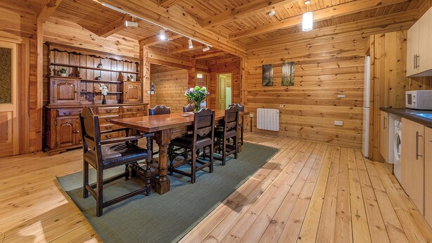 L’intérieur d’un chalet en bois comprend un coin repas, une cuisine et une porte visible qui donne sur l’extérieur.