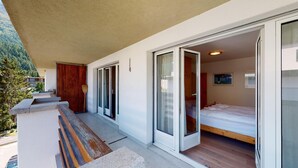 Une chambre moderne avec un grand lit, des portes-fenêtres coulissantes et une vue sur une zone boisée.