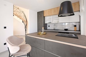 A modern kitchen with a central island, a built-in oven, and a stainless steel sink.
