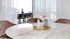 A dining area with a marble table, a vase with flowers, and a tray with glasses and bottles. - Beachfront villa Senses for 12 in Milna (Milna)