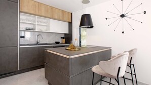 A modern kitchen with a central island, a black pendant light, and a unique wall clock. - Beachfront villa Senses for 12 in Milna (Milna)