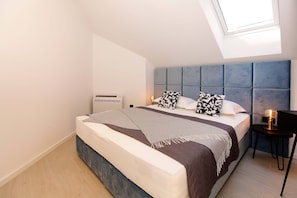 Une chambre moderne avec un lit, une table de chevet et une lucarne.