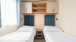 Habitación doble con dos camas, un estante de madera arriba y una mesita de noche.