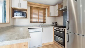 Cocina compacta con lavavajillas, estufa, horno y refrigerador.