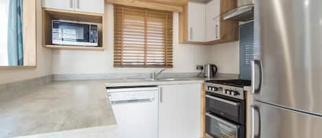 A compact kitchen with a dishwasher, stove, oven, and a refrigerator.