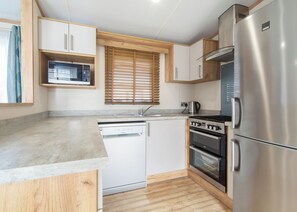 A compact kitchen with a dishwasher, stove, oven, and a refrigerator.