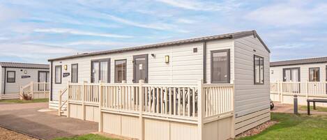 A single-story mobile home with a front deck, a small porch, and a visible garage door.