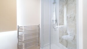 Eine moderne Dusche mit Glastür, Marmorwand und einem Metallhandtuchhalter.