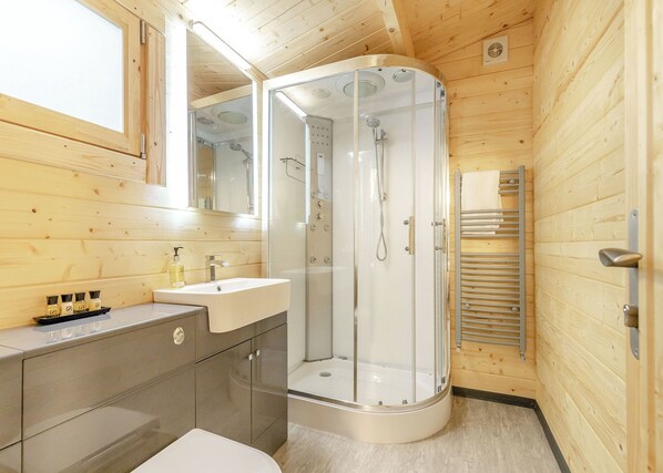A modern bathroom with a glass-enclosed shower, a sink with a mirror, and a towel rack.