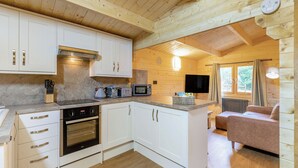 A compact kitchen with white cabinets, a built-in oven, and a microwave. - 1 bedroom accommodation in Freehay, Cheadle (Freehay, Cheadle)