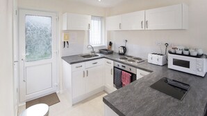 Une cuisine moderne avec des meubles blancs, un plan de travail en granit, une cuisinière, un four à micro-ondes et un grille-pain.