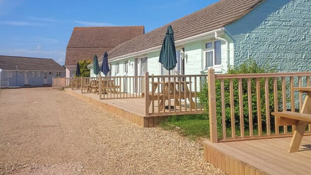 Une rangée de petits chalets situés au bord de la plage, dotés de terrasses en bois et de parasols.