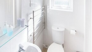 Une salle de bain moderne avec une étagère en verre, des carreaux blancs, des toilettes et une fenêtre.