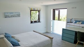 Ein Schlafzimmer mit Bett, Schreibtisch, Stuhl, Fenster und einem Bild an der Wand.
