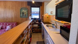 Une cuisine de taille réduite, dotée de meubles en bois, d’un four à micro-ondes et d’un évier.