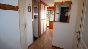 Ein Flur mit Holzboden, weißen Wänden und einer Tür mit Spiegel.