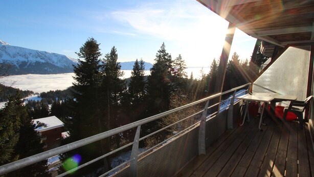 Eine Holzterrasse mit Blick auf verschneite Berge und einen See.