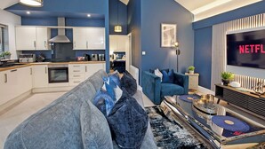 Ein modernes Wohnzimmer mit einer Couch, einem Couchtisch und einem Fernseher, der 'NETFLIX' anzeigt.