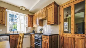 Une cuisine avec des meubles de rangement en bois, une cuisinière et un lave-vaisselle.