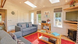 A cozy cabin interior with a sofa, a coffee table, a fireplace, and skylights. - Luxurious and contemporary lodge with stunning countryside views. (Ashover)