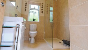 A modern bathroom with a glass shower enclosure, a toilet, and a sink. - Lodge with one king-size double with TV. (Newby Bridge, Lake Windermere)